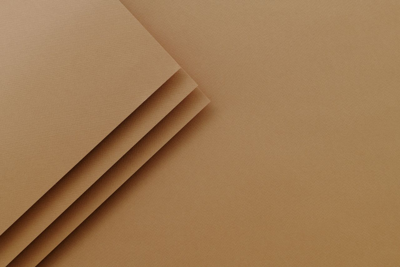The Art of Drawing Readers In: Your attractive post title goes here A close-up of layered brown paper creating a minimalist textured background with copy space.